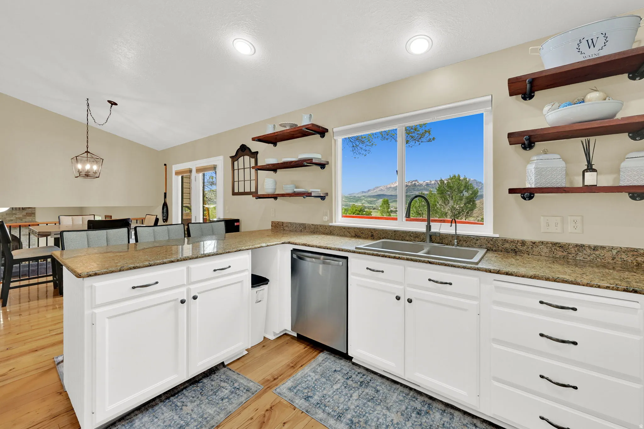 Kitchen featuring white cabinetry with dark hardware, granite-look countertops, and wood-finish flooring