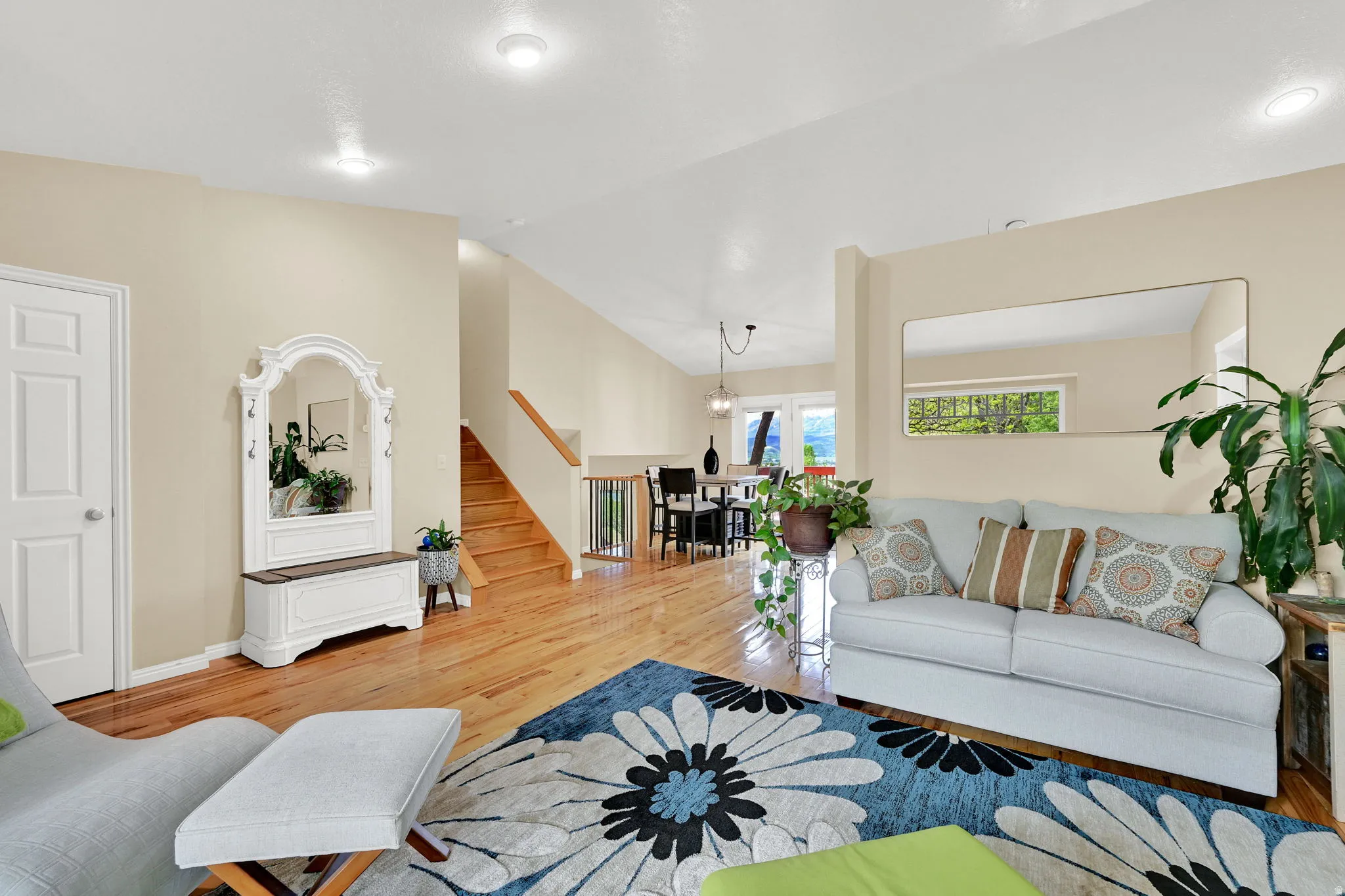 Open-concept living area featuring wood-finish flooring, a neutral color palette, recessed lighting, and a white panel door