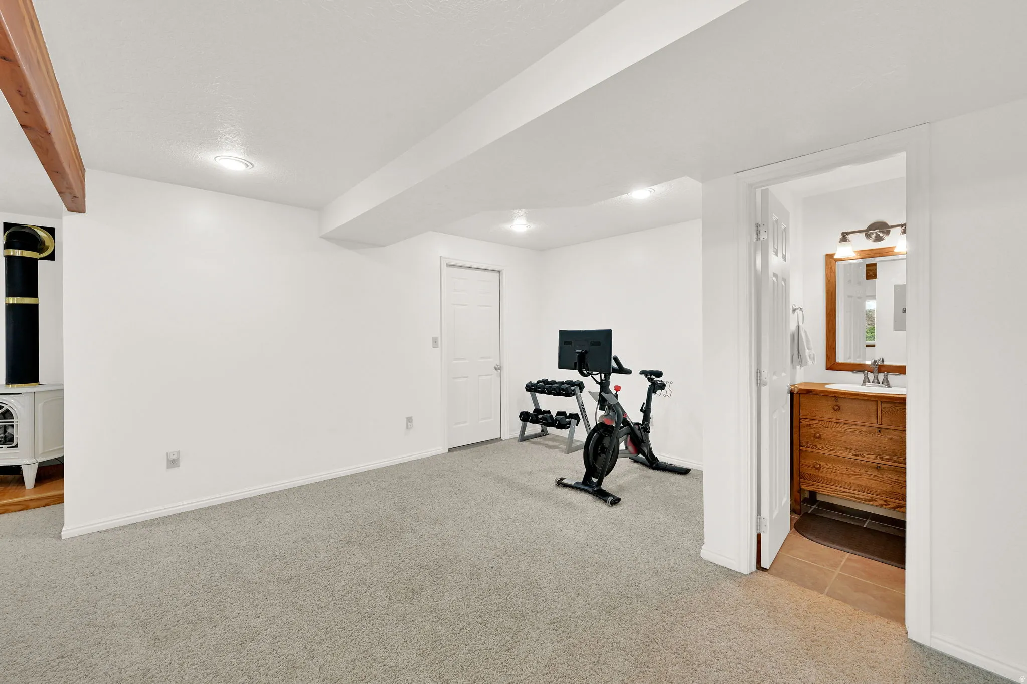 Spacious room with plush carpeting, recessed lighting, and a prominent wood-finish beam