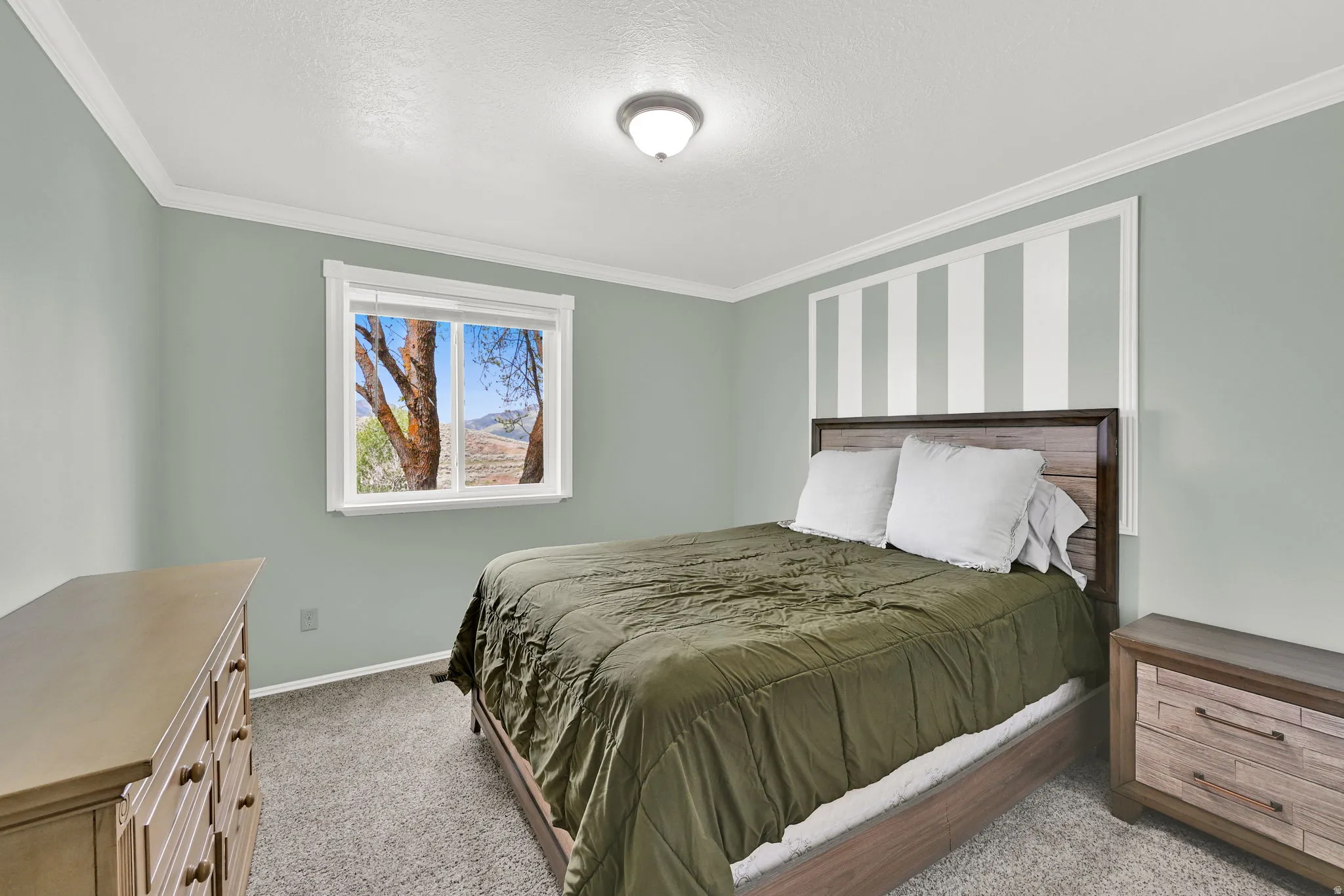 Bedroom featuring a window with a mountain backdrop, crown molding, and textured carpet flooring