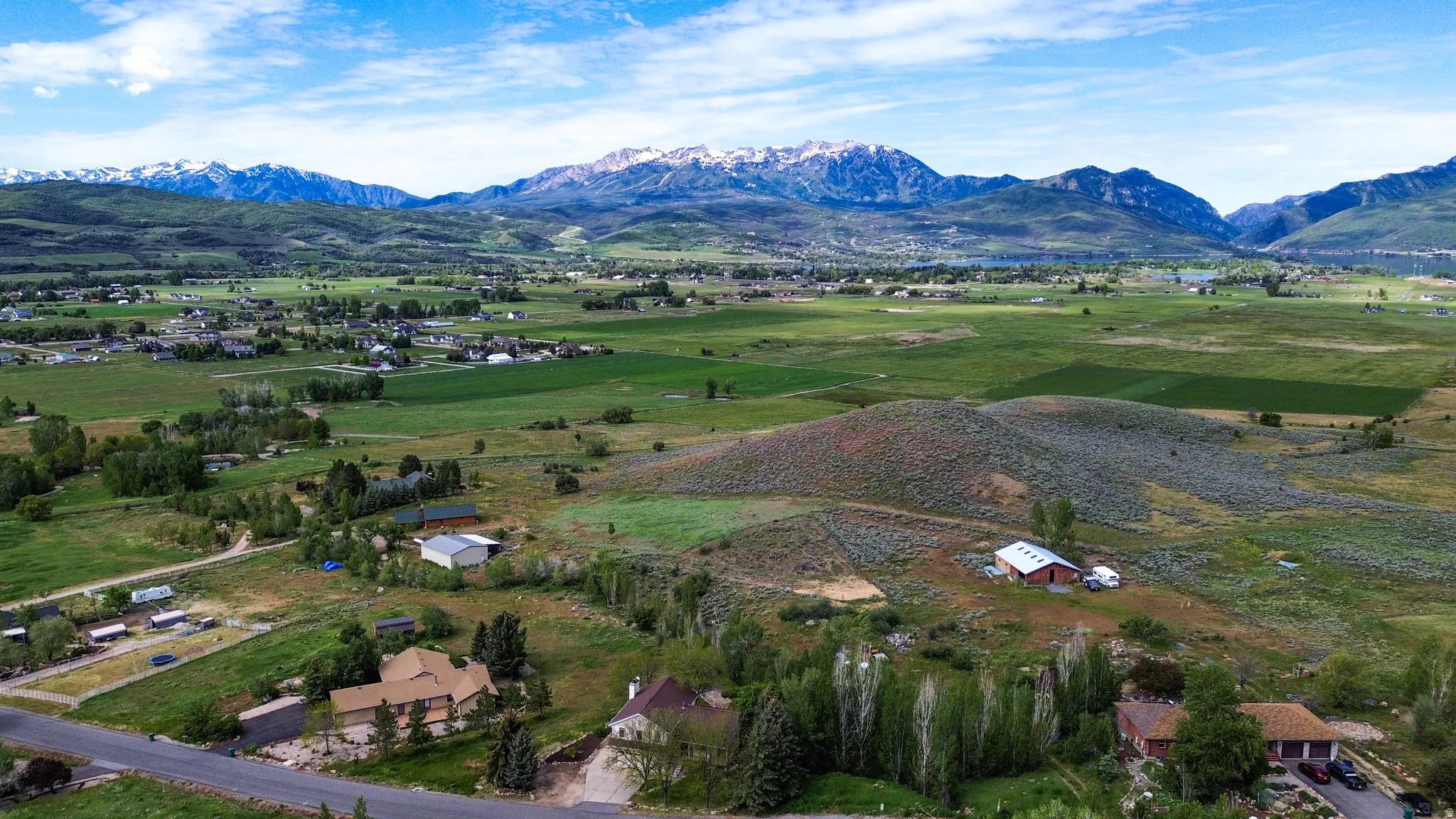 Expansive rural landscape featuring distant snow-capped mountains and scattered residential properties