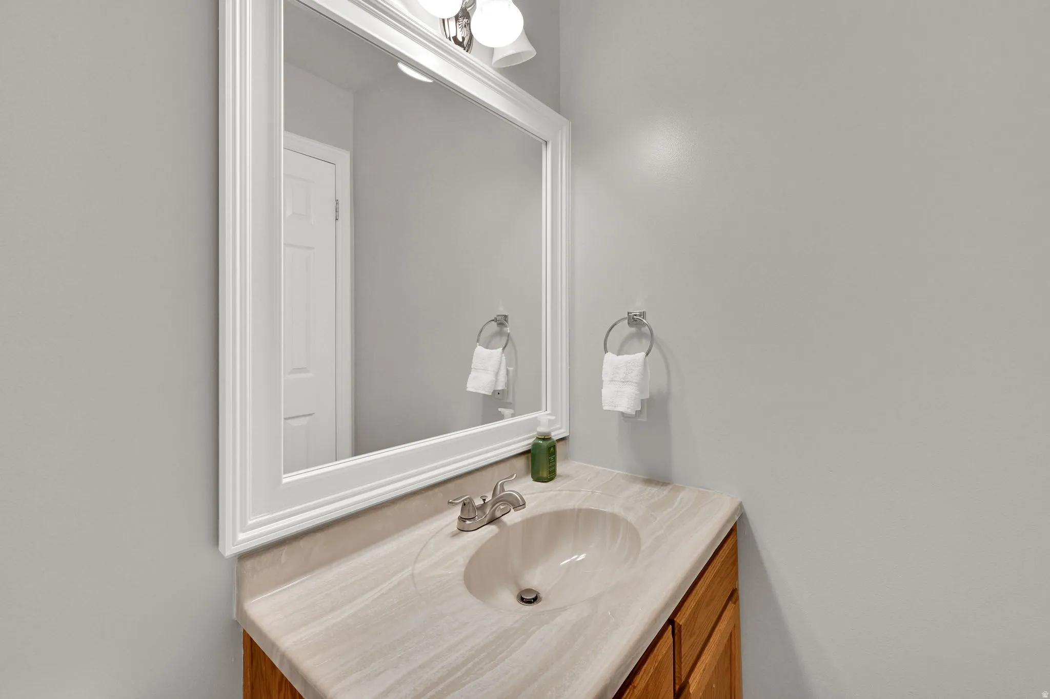 Bathroom vanity featuring a light-toned countertop, an integrated sink, and a chrome faucet