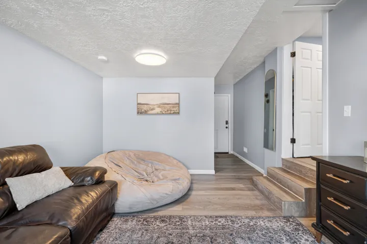 Recessed lighting illuminates the wood-finish flooring and light gray walls