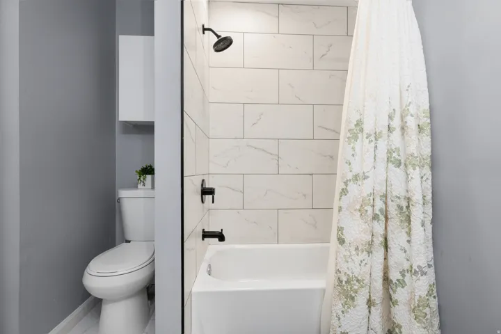 Bathroom featuring a white subway-tiled shower surround, a white bathtub, and matte black fixtures