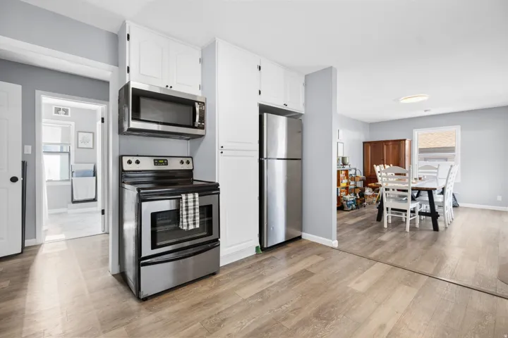 Kitchen area featuring white cabinetry, stainless steel microwave, and stainless steel range