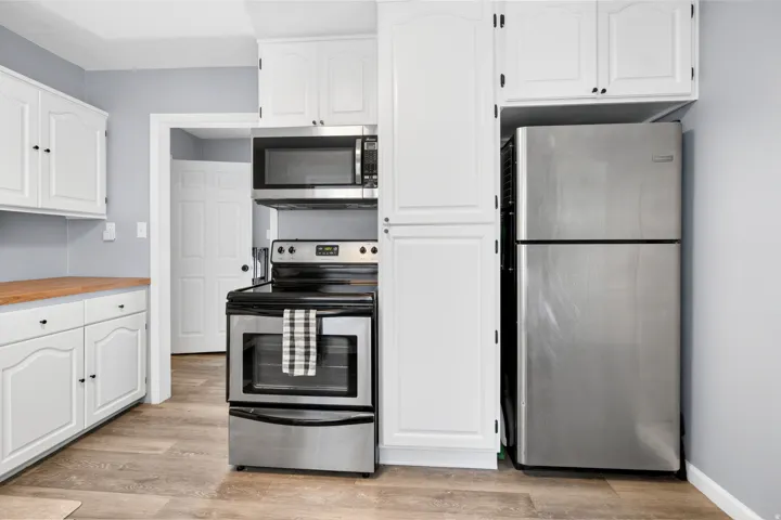 Kitchen featuring white cabinetry with black hardware, wood-finish countertops, and stainless steel appliances