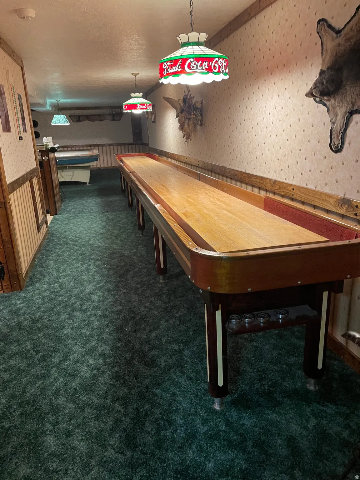 Recreation area featuring a shuffleboard table, patterned wallpaper, and wood paneling
