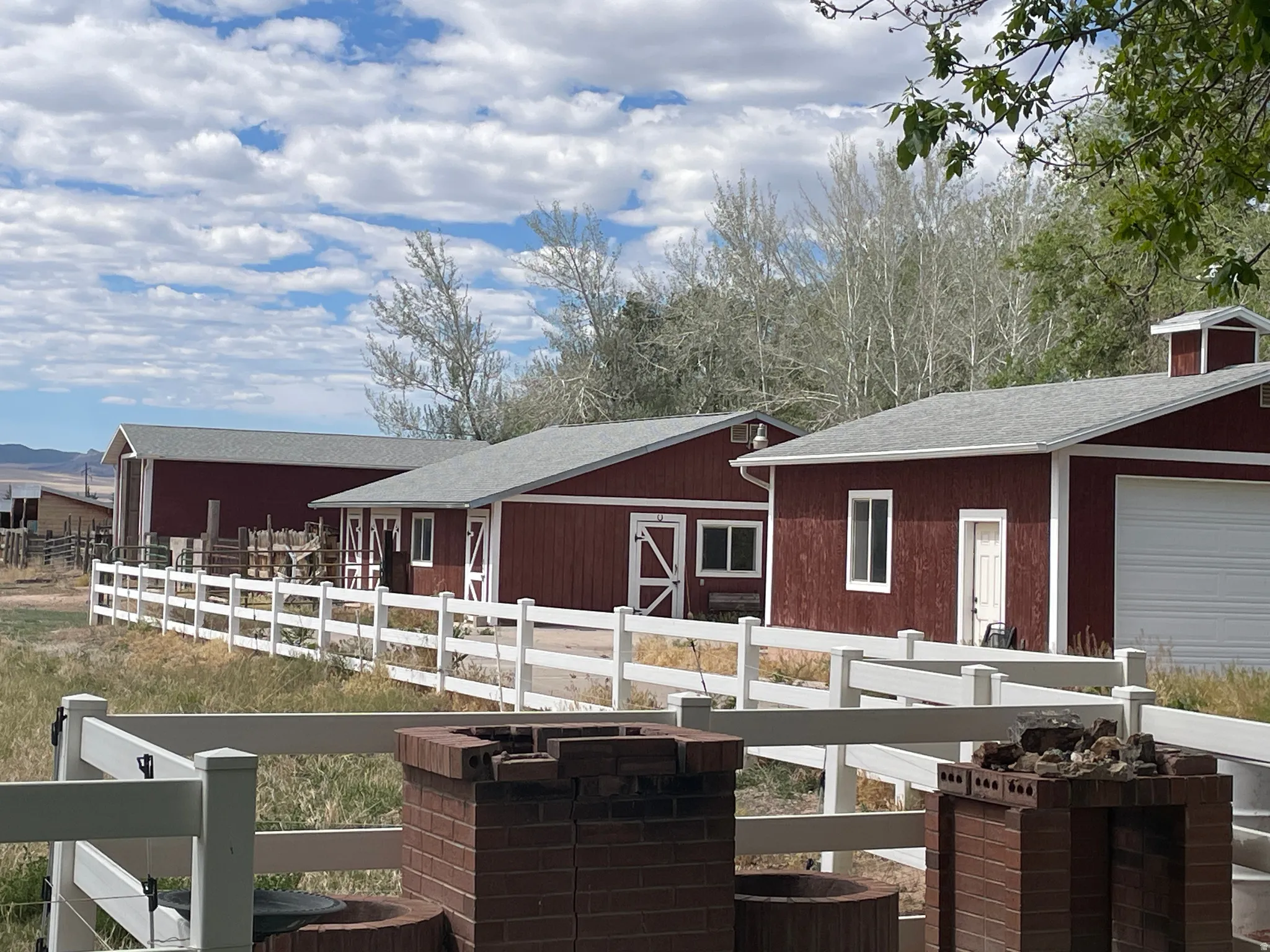 Distant RV Garage, Wood shop and Detached 2 car Garage all red-sided  with white trim, gray shingle roofs, and white fencing