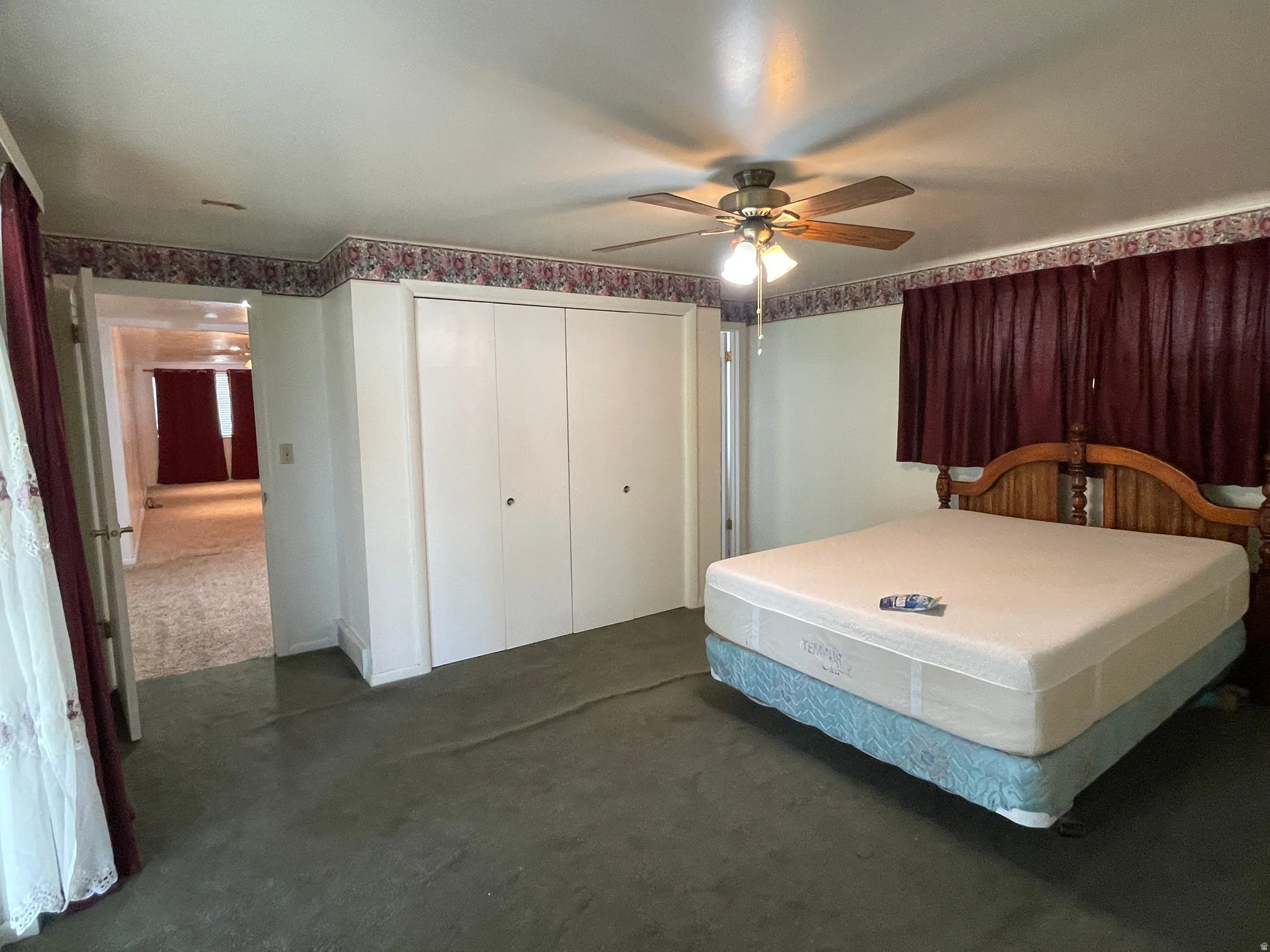 Carpeted room featuring a ceiling fan with integrated lighting, full-height double door closet, and an ornate wood headboard