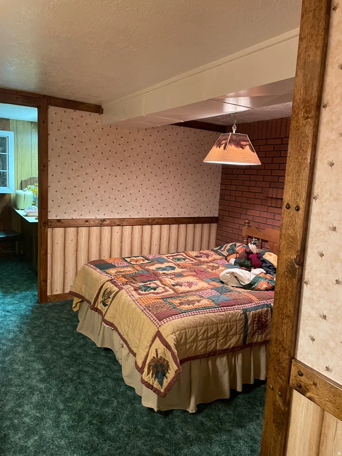 Room featuring textured wallpaper, wood paneling, and a brick accent wall