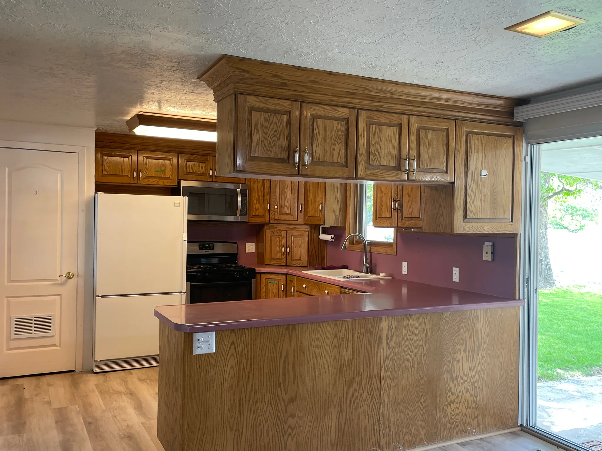 Kitchen featuring wood-finish cabinetry, stainless steel microwave, black gas range, and light wood-finish flooring
