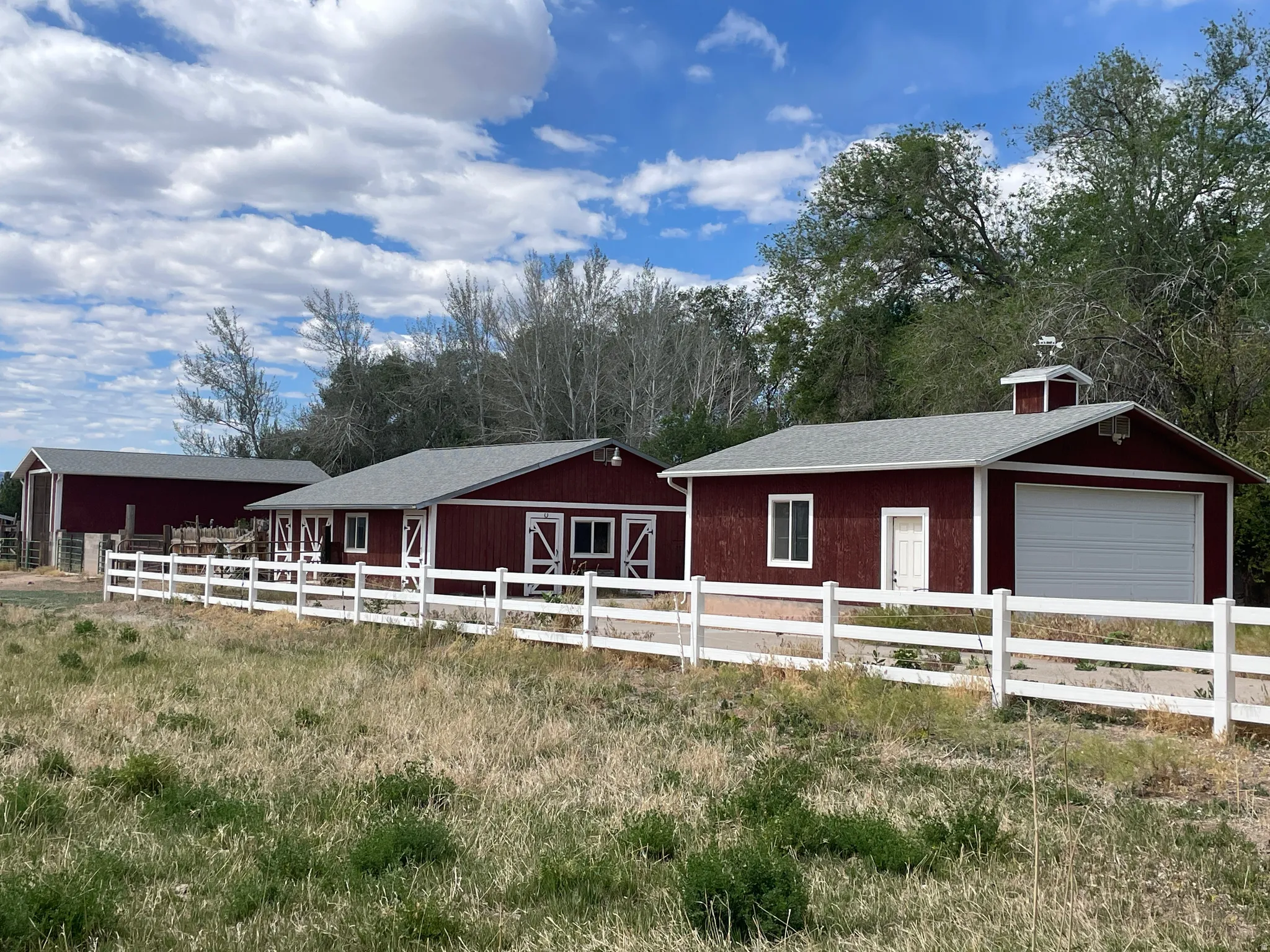 Red-painted outbuildings with white trim and a white fence line