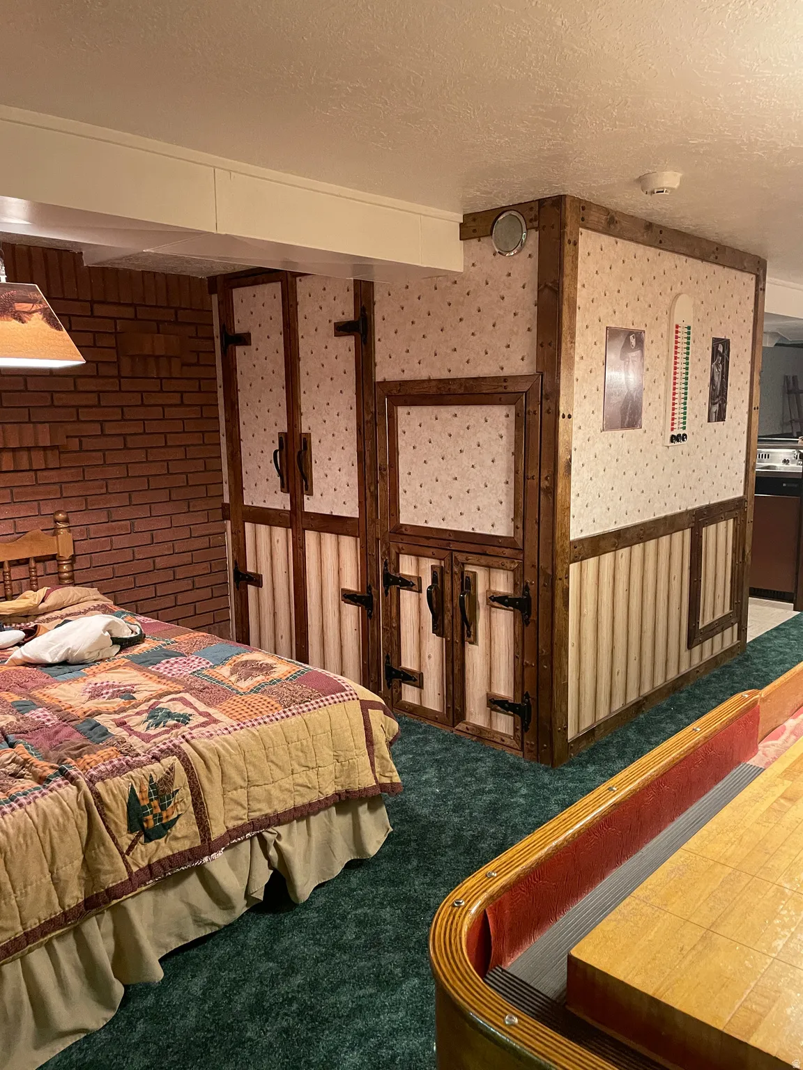 Finished space featuring a brick accent wall, wood-paneled structural elements, and plush green carpeting