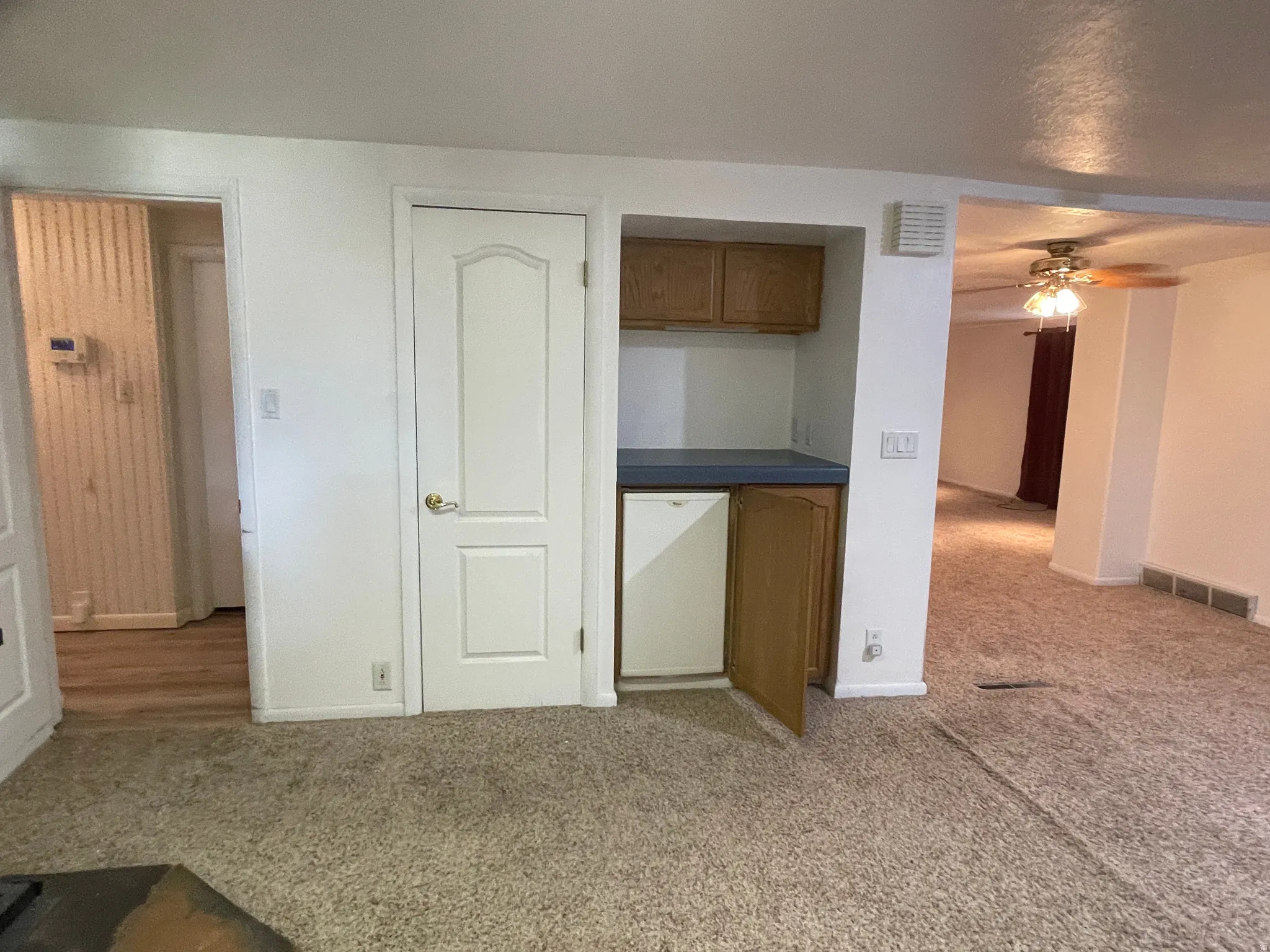 Built-in wet bar featuring upper and lower cabinetry with a solid surface countertop and fridge.