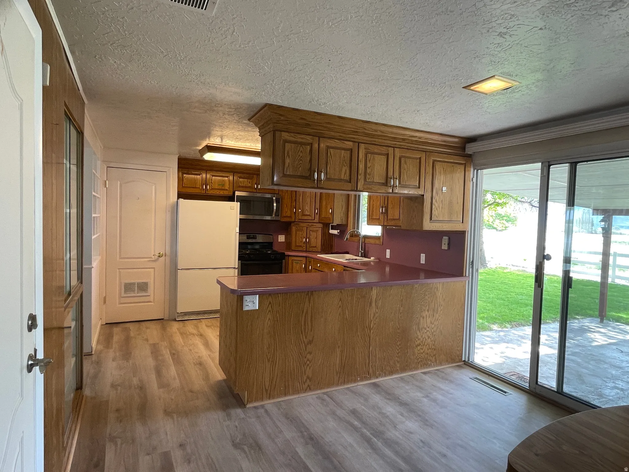 Kitchen featuring wood cabinetry, a breakfast bar, and sliding doors to covered patio.