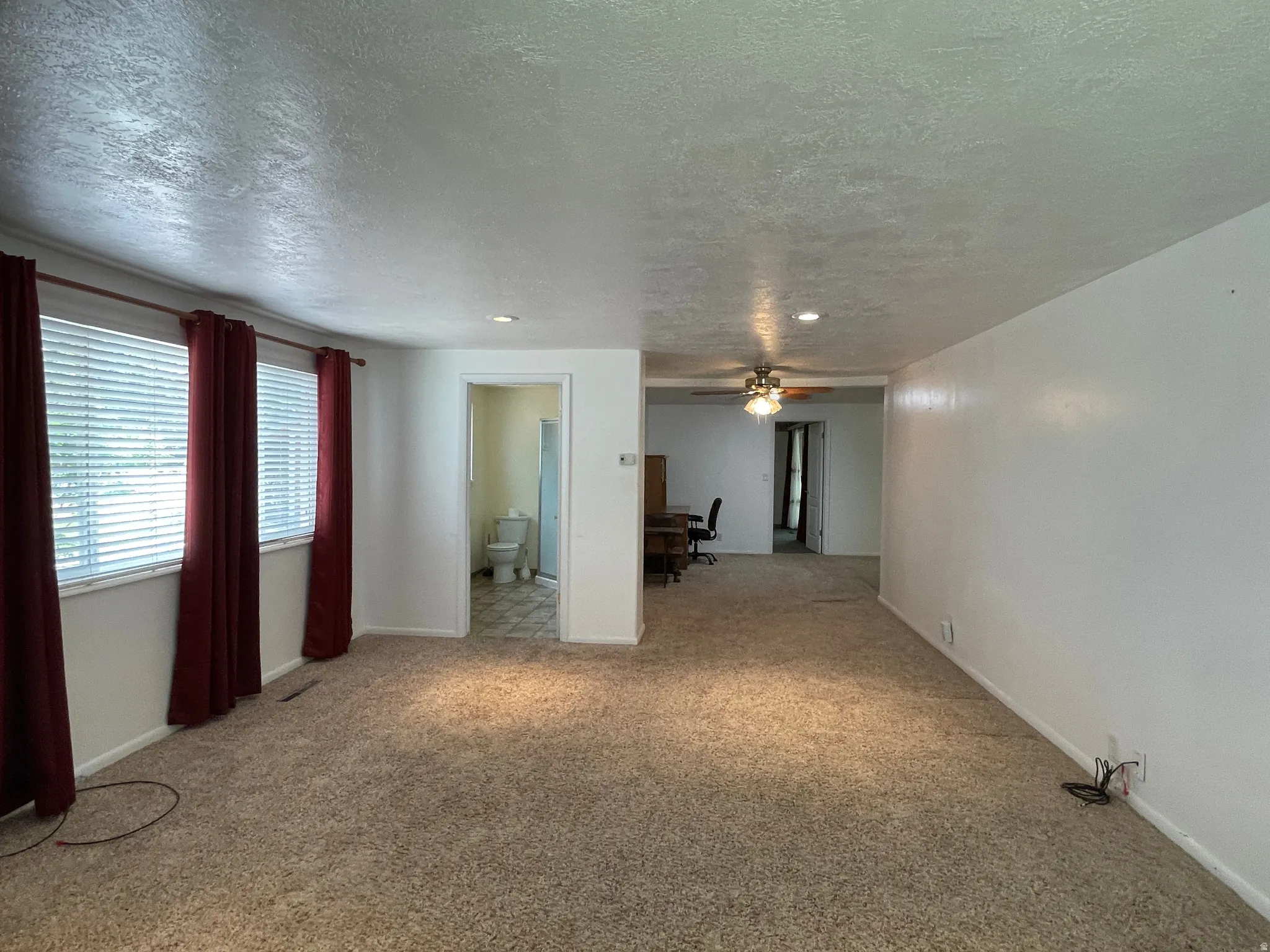 Spacious second sleeping area in Primary Suite featuring carpet flooring, multiple windows with blinds, a recessed ceiling light, and access to a bathroom with tile flooring
