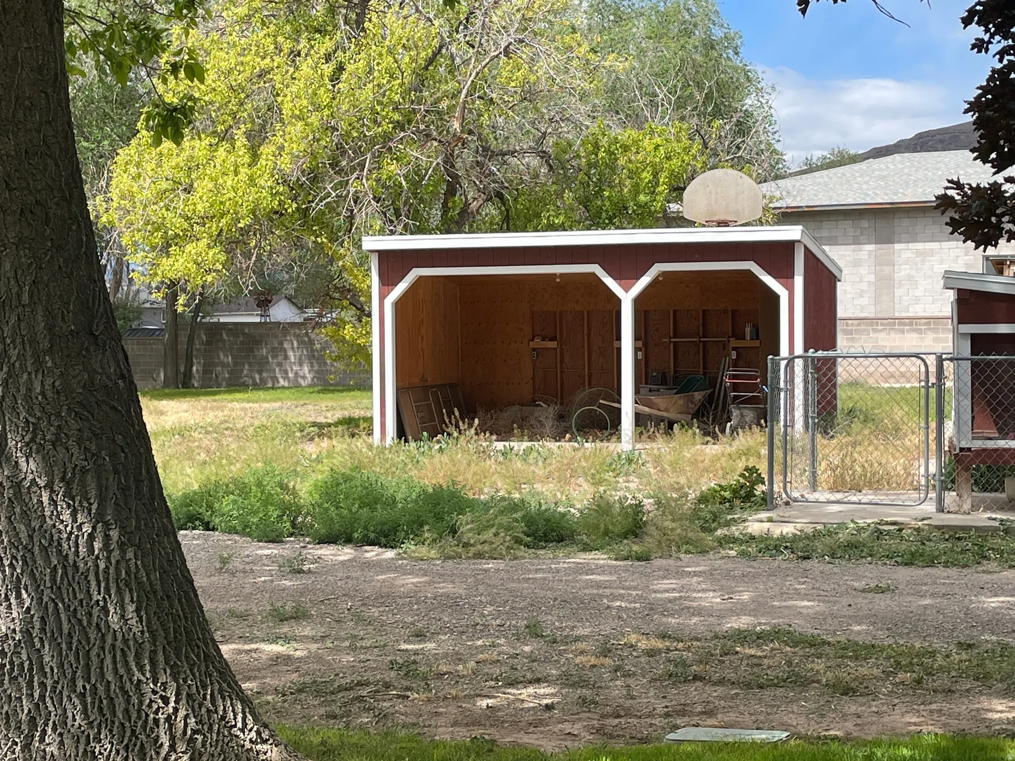 Red-painted outbuilding featuring white trim and two open bays to park the ORV's
