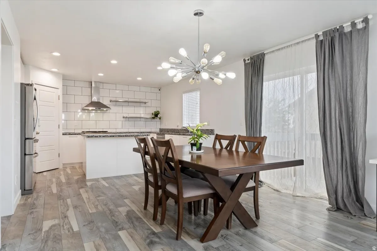 Open-concept dining area featuring wood-finish flooring and a contemporary chandelier
