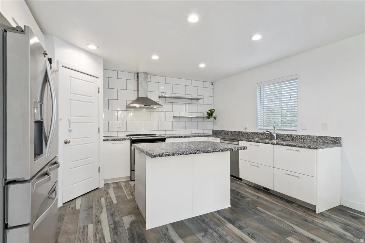 Modern kitchen featuring a central island with a granite-style countertop, complemented by white flat-panel cabinetry