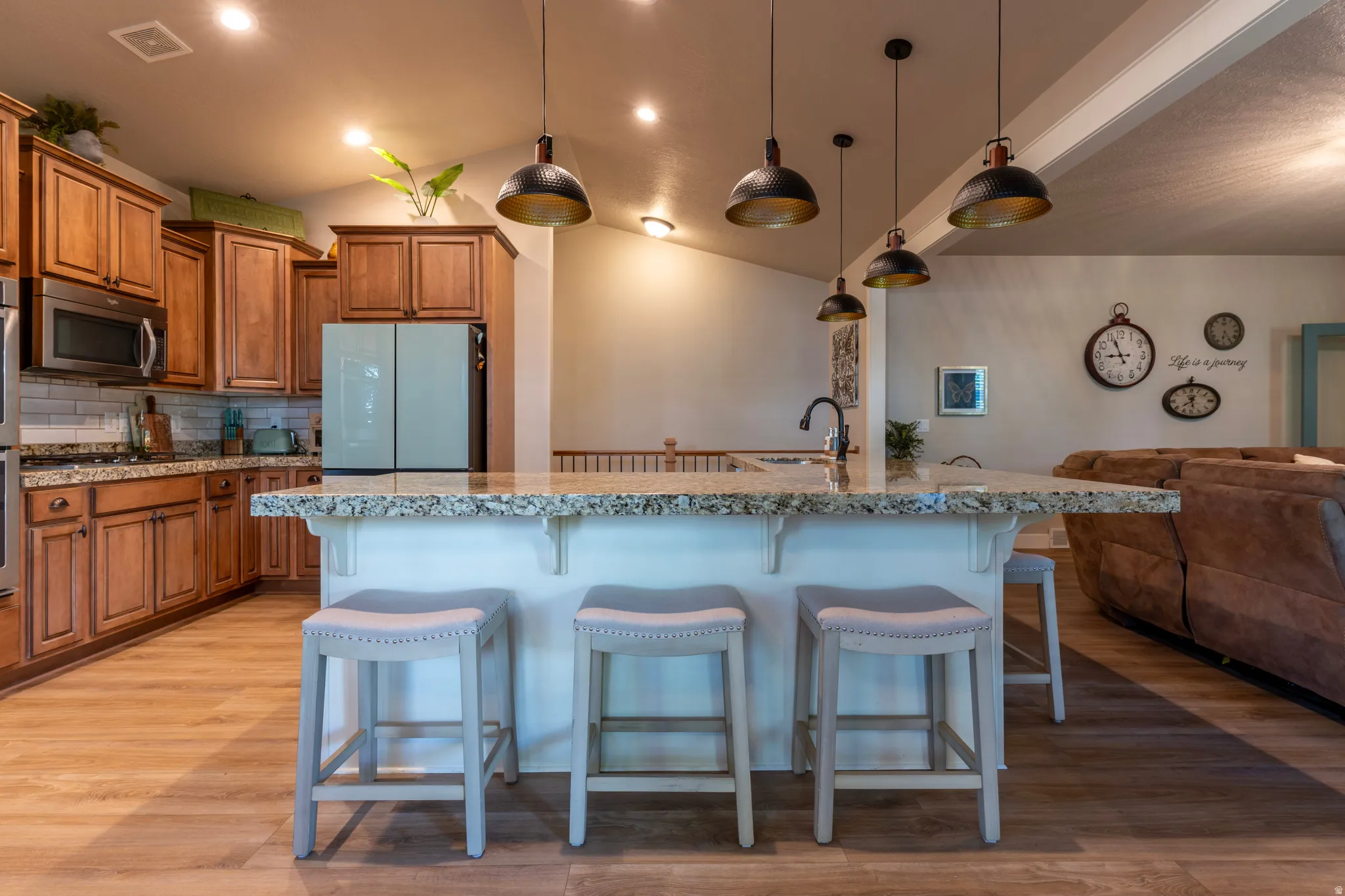Kitchen island with granite countertop and integrated sink, complemented by wood-finish flooring