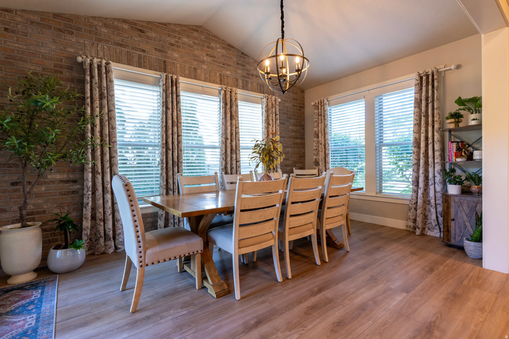Dining area featuring a vaulted ceiling and an exposed brick accent wall
