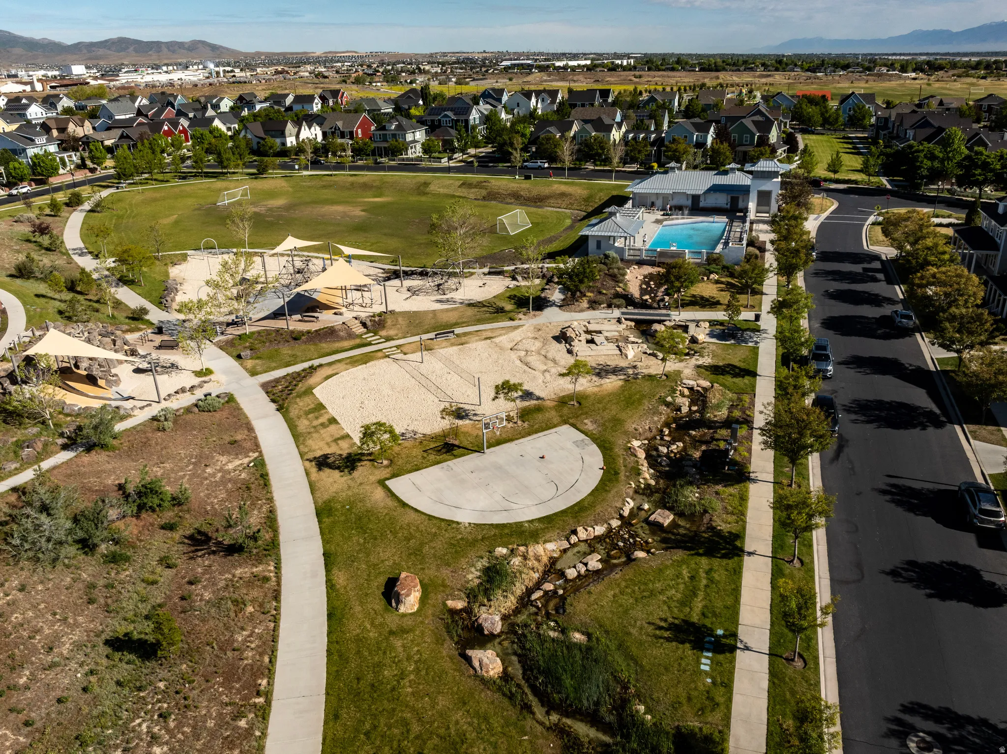 Community amenities featuring a swimming pool, sports fields, sand recreation areas, and walking paths