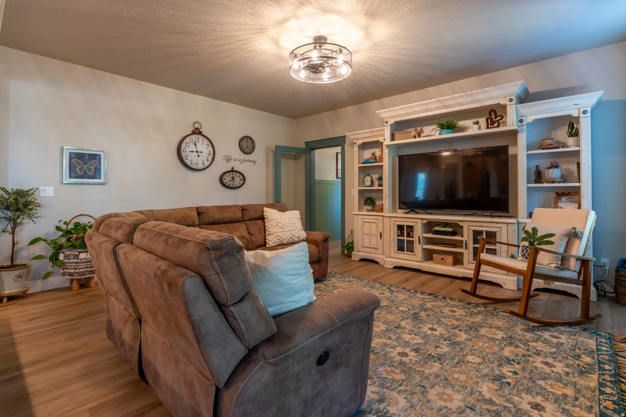 Living area featuring wood-finish flooring, a decorative ceiling fixture, and light-toned wall paint