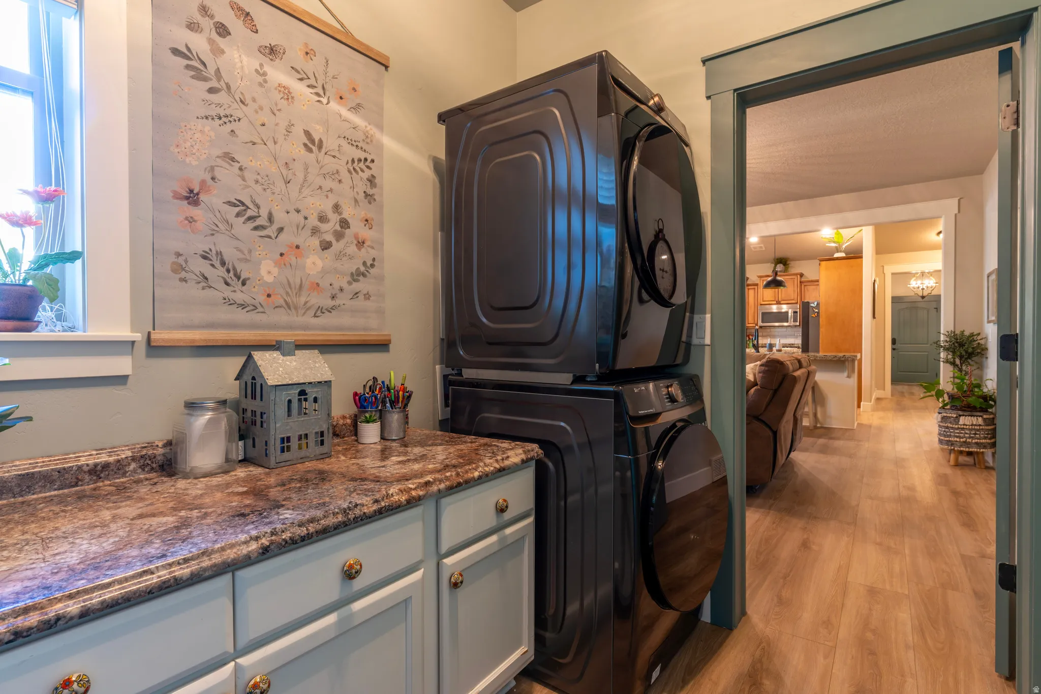 Laundry area featuring a stacked washer and dryer, light blue cabinetry with decorative knobs, and a patterned countertop