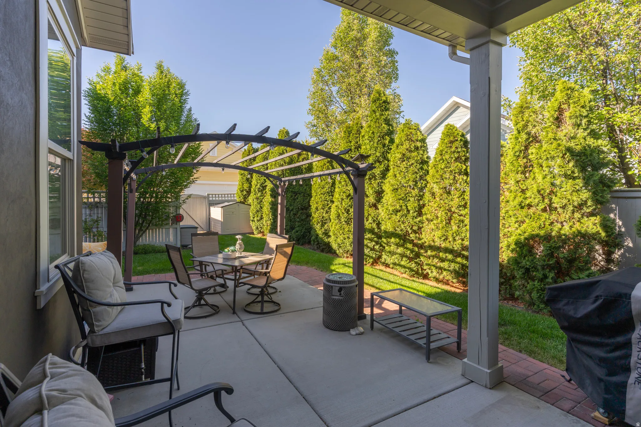 Expansive patio featuring a concrete surface, a decorative metal pergola, and a brick paver border