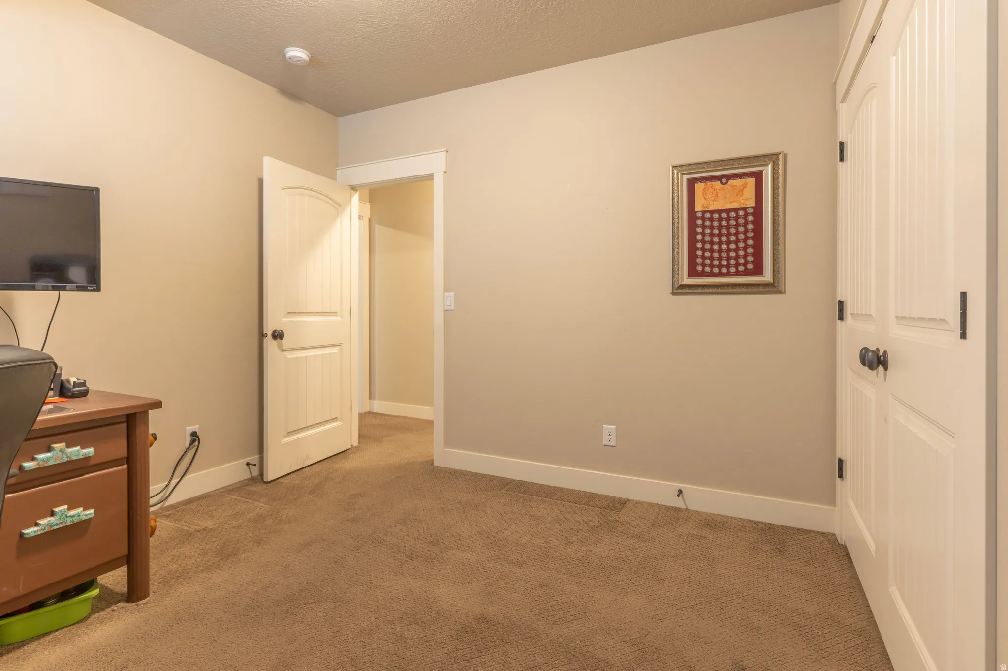Carpeted room with neutral wall tones and white baseboards