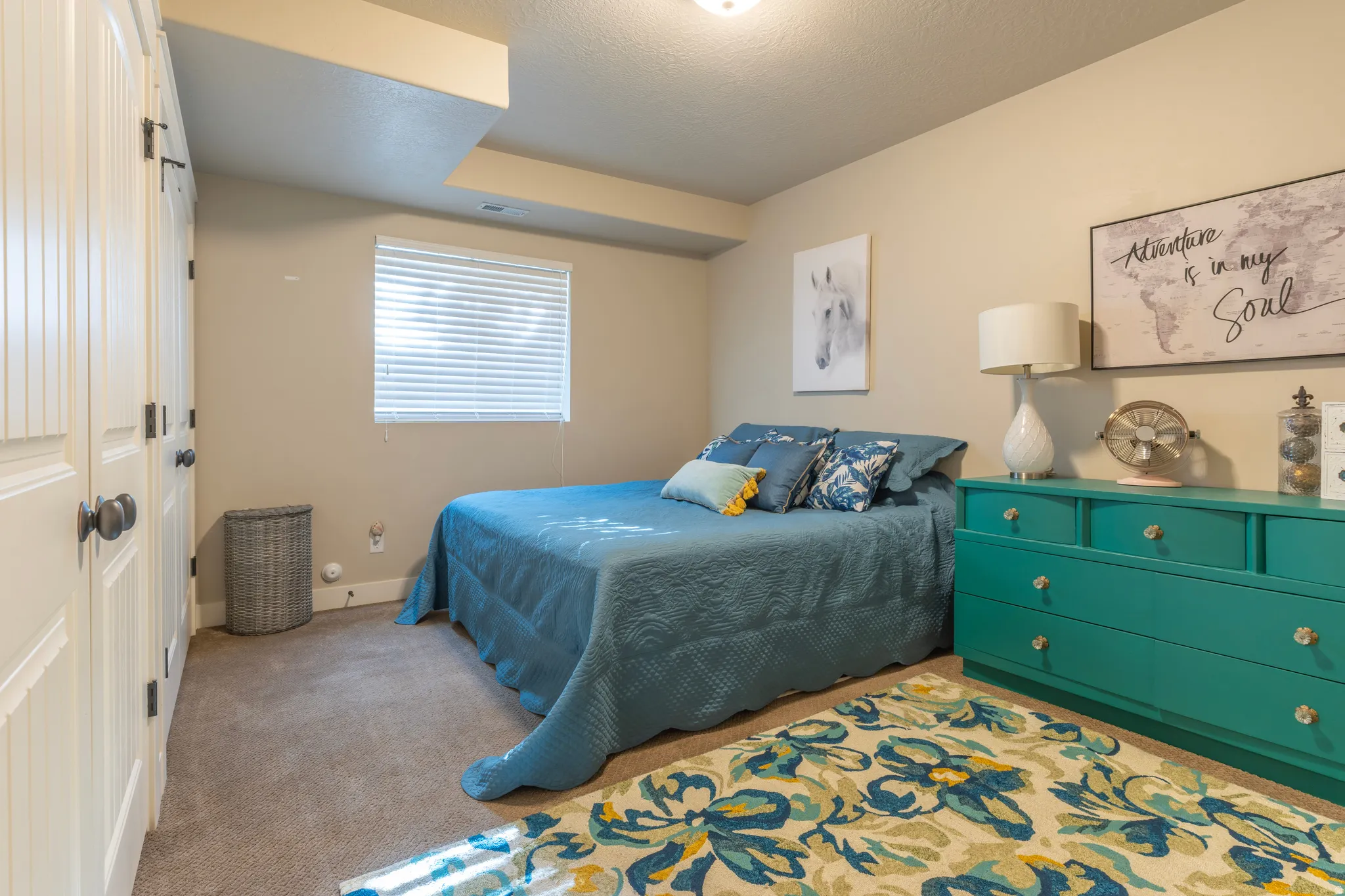 Bedroom featuring neutral wall paint, carpet flooring, a window with blinds, and white bi-fold closet doors
