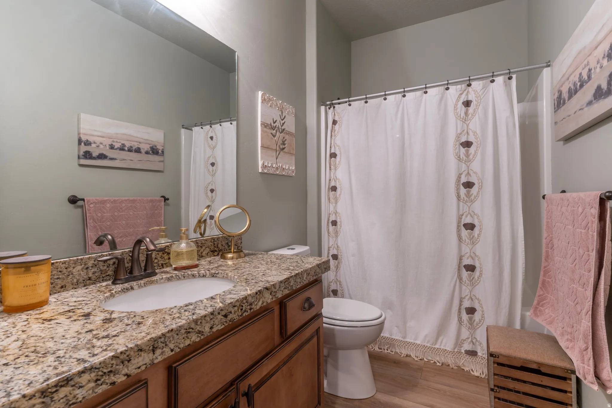 Bathroom with a granite-style countertop, integrated sink, and wood-finish vanity