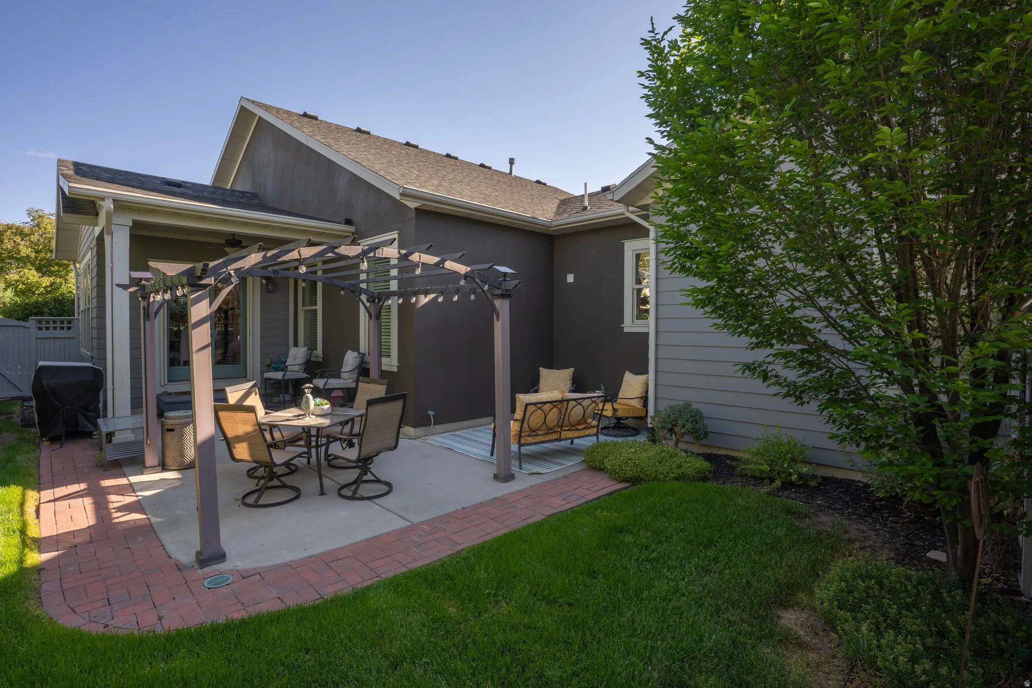 Outdoor patio featuring a pergola, concrete slab, and brick paver border