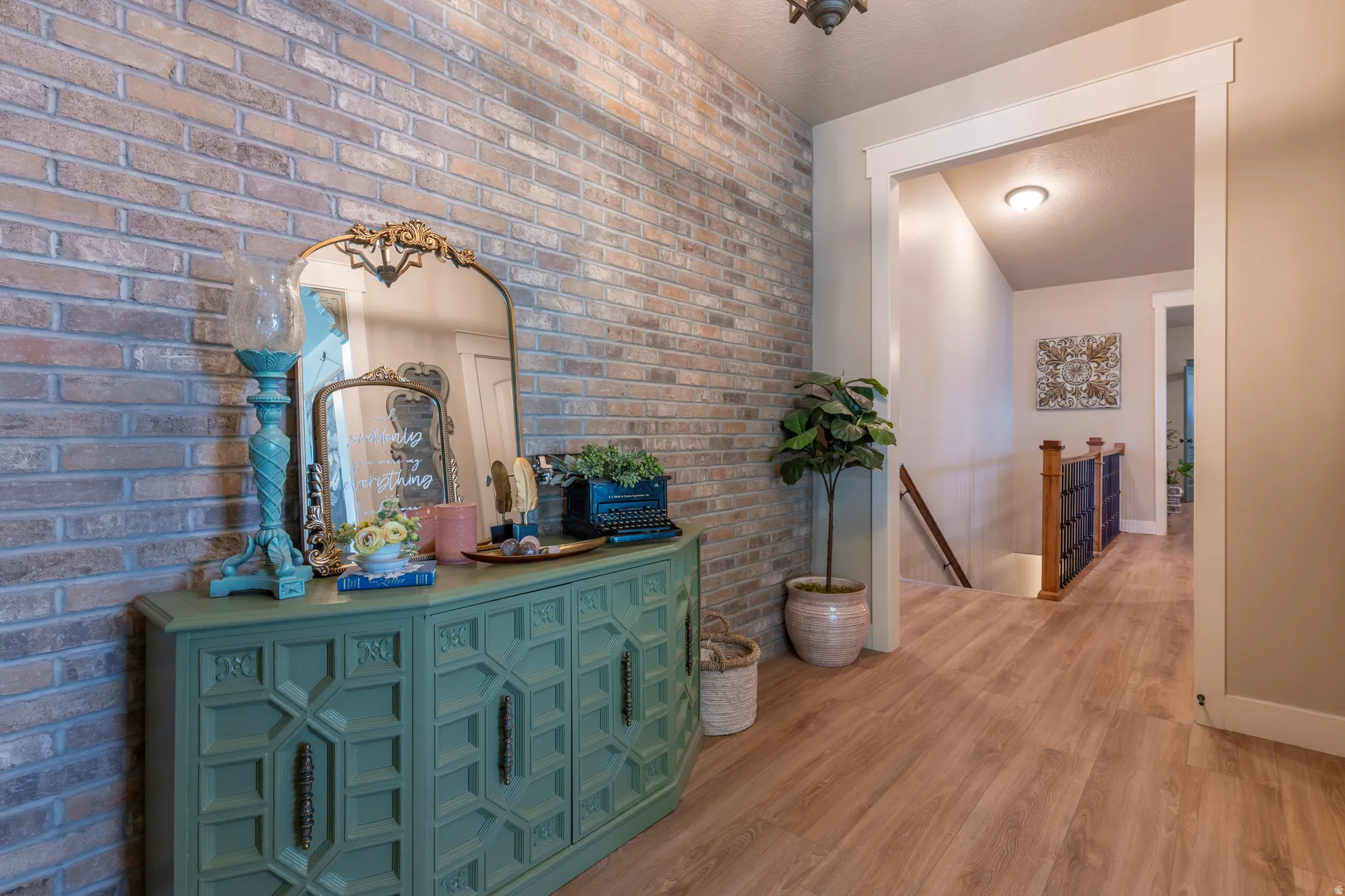 Entryway featuring a brick accent wall, wood-finish flooring, and crisp white trim