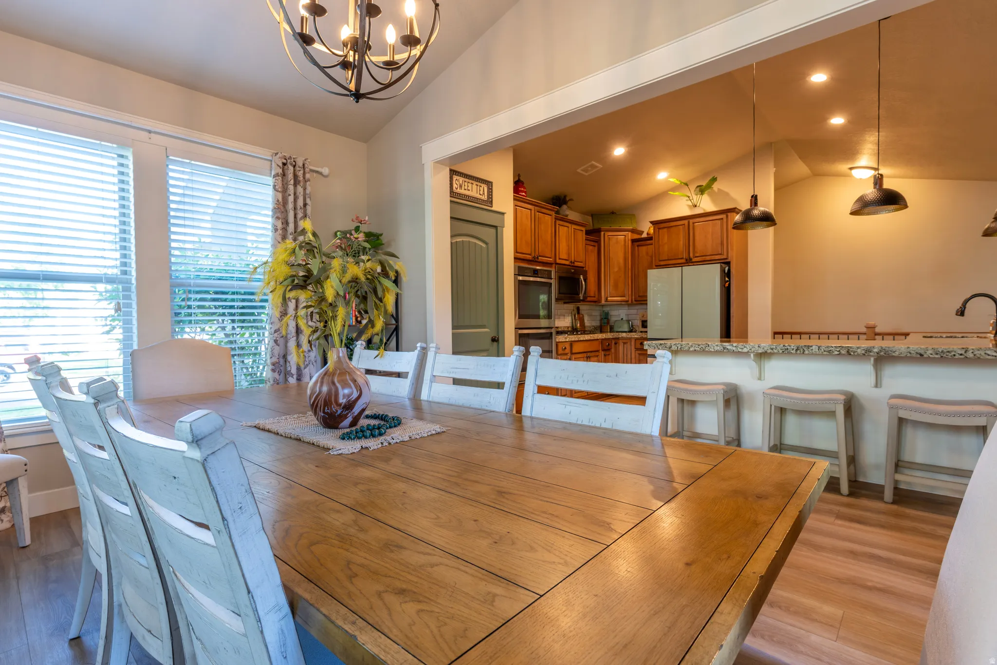 Open-concept living space featuring a dining area with a vaulted ceiling and an iron chandelier