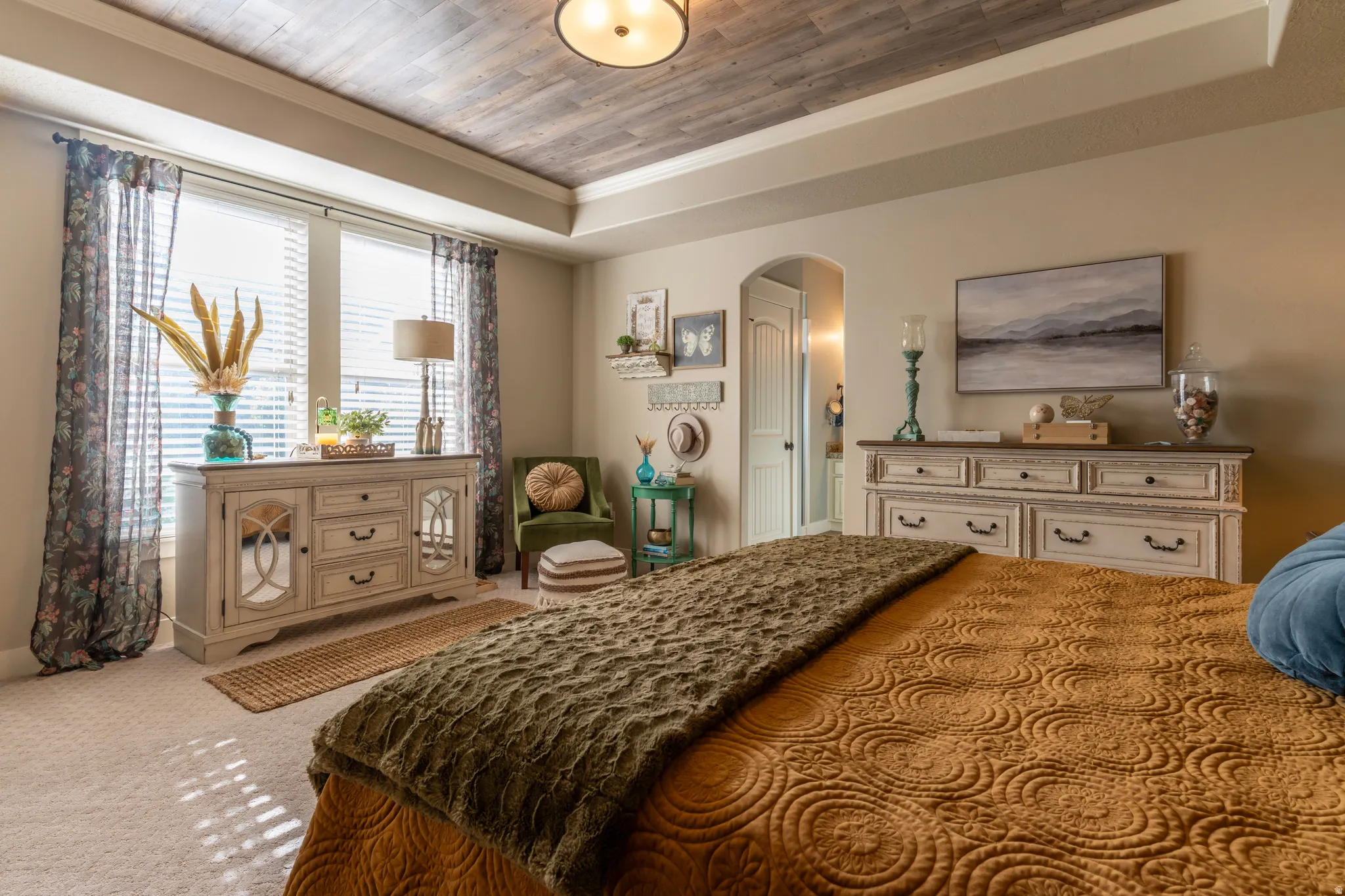 Recessed tray ceiling with wood-finish paneling, arched doorway, and soft neutral wall tones