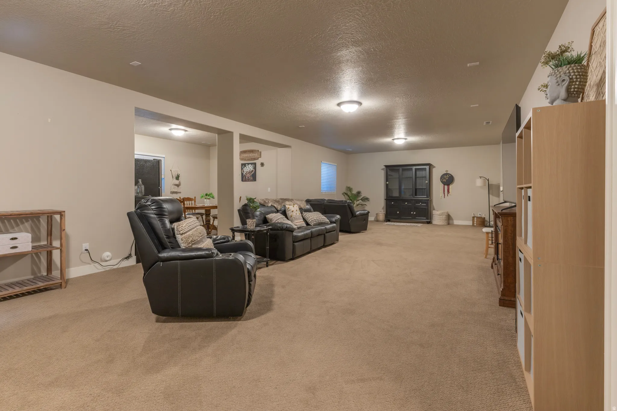 Expansive carpeted room with neutral wall tones and recessed lighting