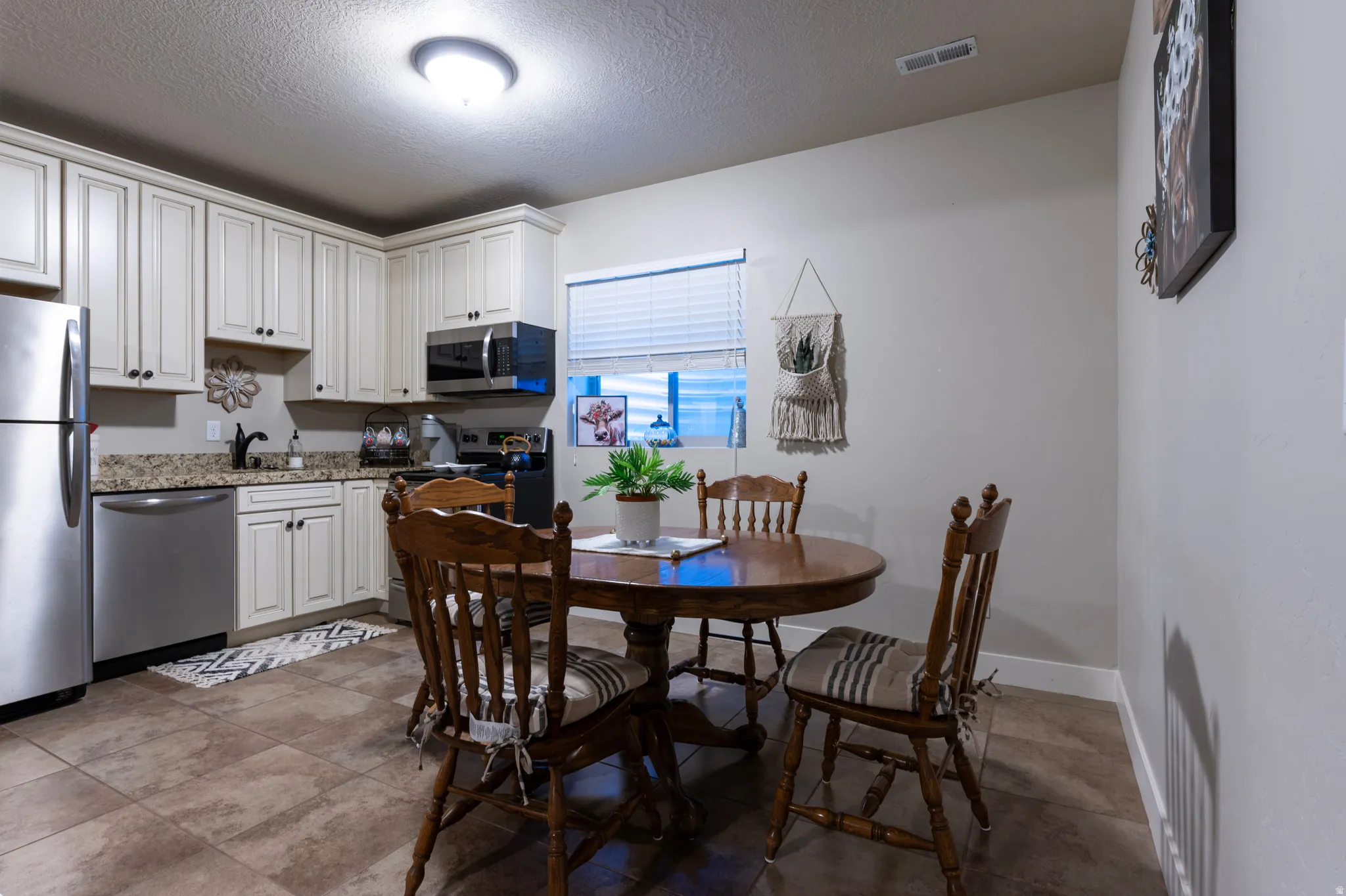Kitchen featuring white cabinetry, granite countertops, stainless steel appliances, and tile flooring