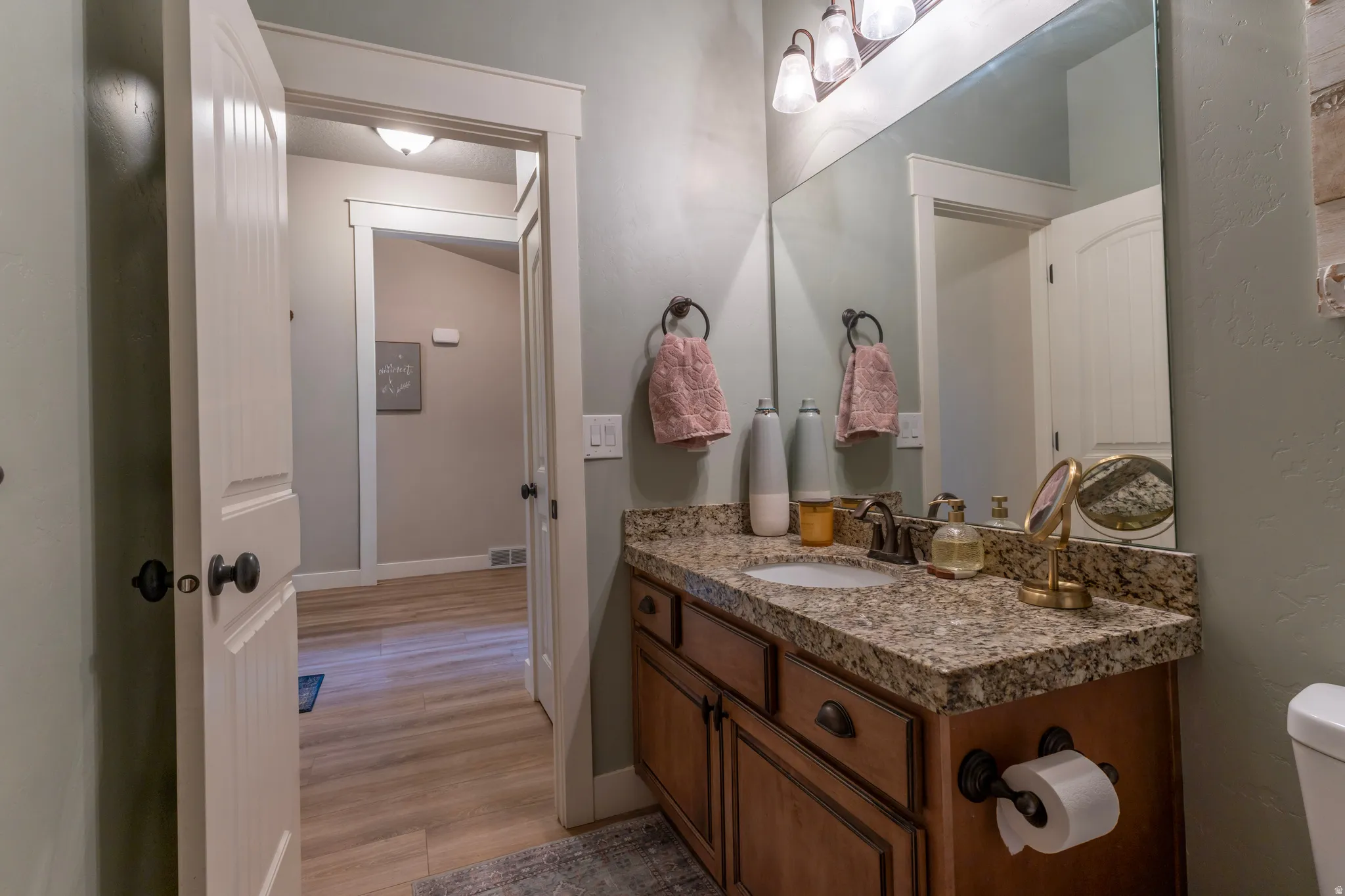 Bathroom featuring a vanity with a granite countertop, undermount sink, and wood-finish cabinetry