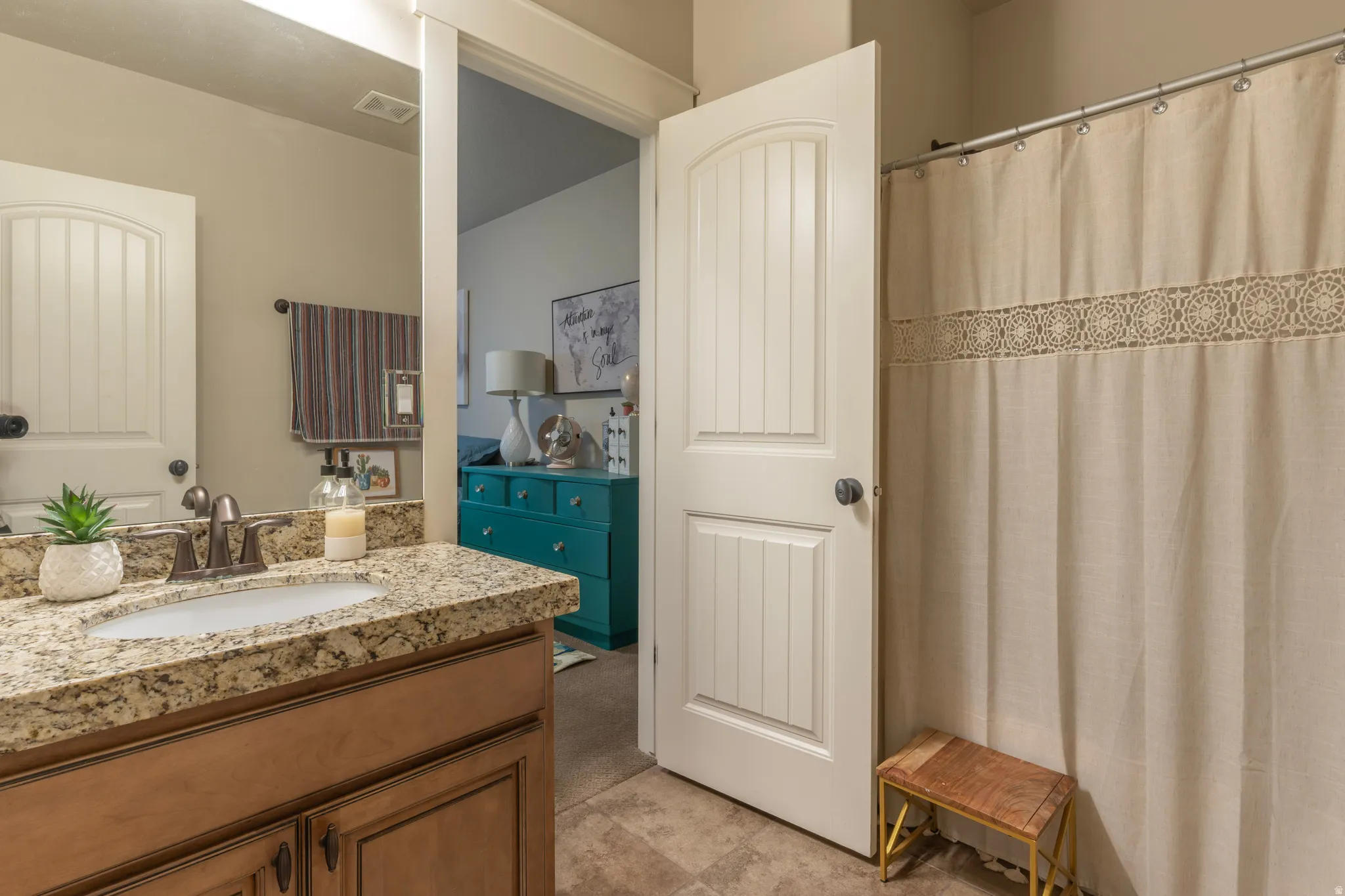 Spacious bathroom featuring a single vanity with stone-finish countertop, undermount sink, and bronze-finish faucet