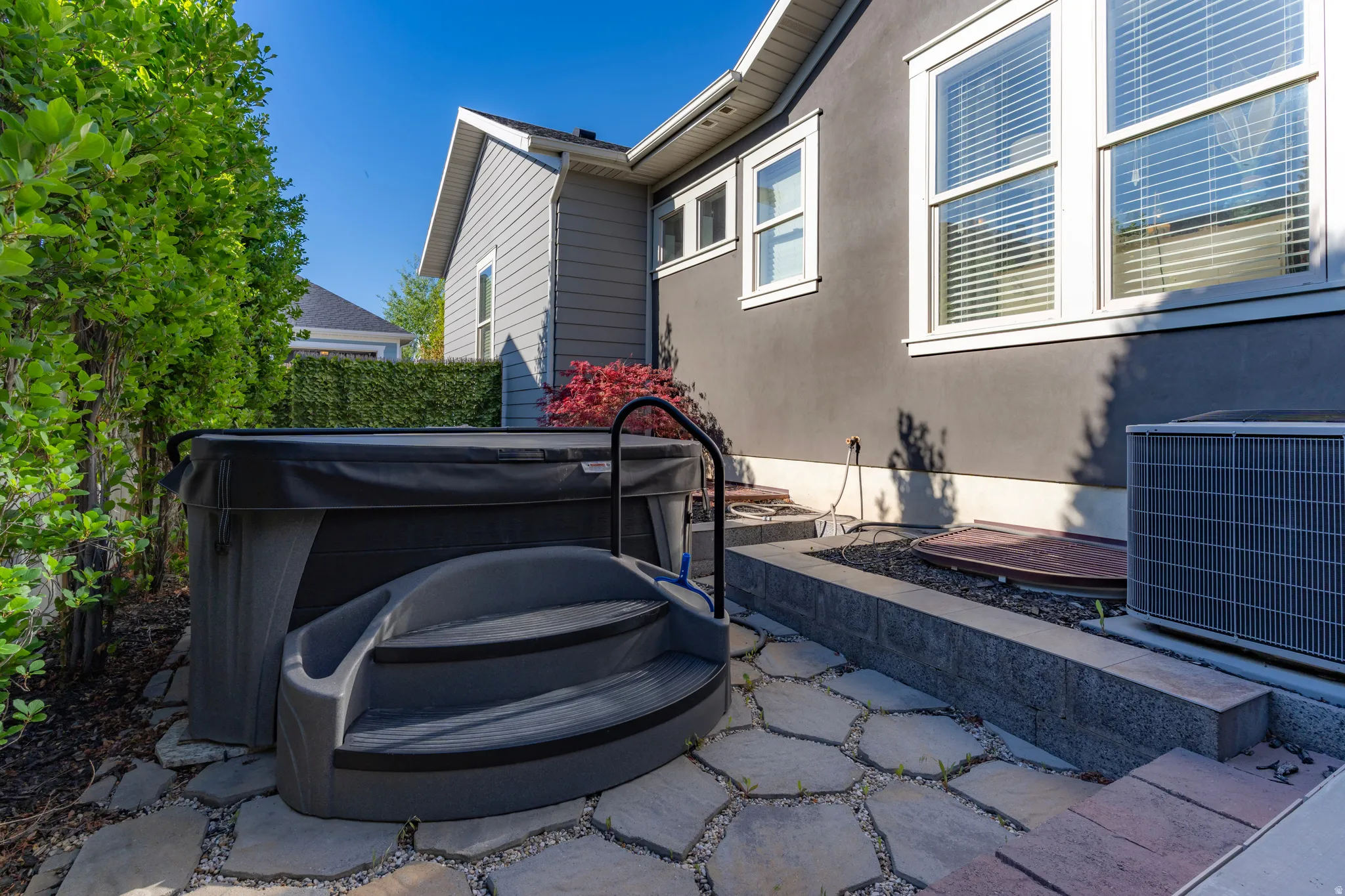 Outdoor spa with integrated steps, surrounded by flagstone paving and mature privacy landscaping