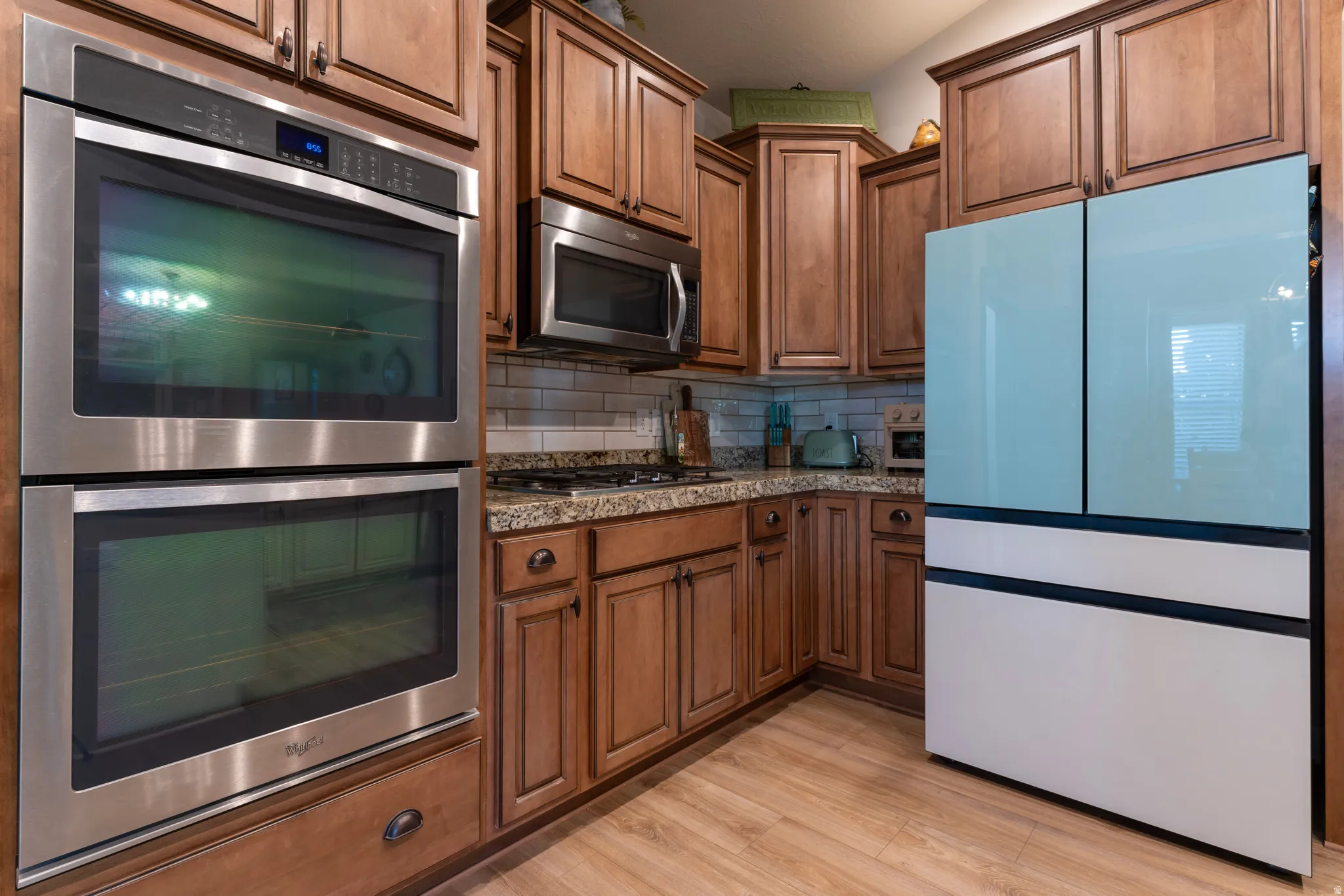 Kitchen featuring wood-finish flooring, granite countertops, and a tiled backsplash