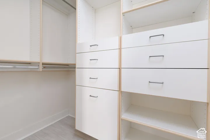 Custom closet system featuring multiple white drawers with dark hardware, open shelving, and hanging rods