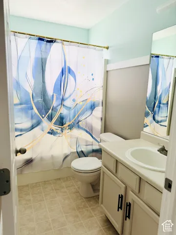Full bathroom featuring a single vanity with storage, an integrated sink, and a commode