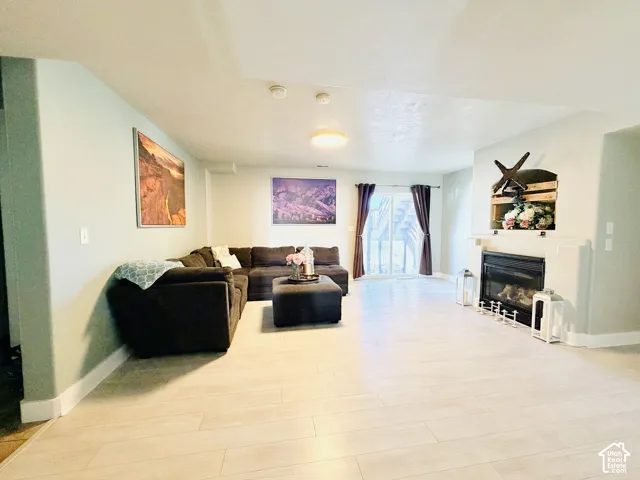 Spacious living area featuring light-toned wood-finish flooring, a built-in fireplace with a hearth, and an inset decorative shelf above the mantel