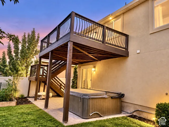 Multi-level deck with decorative railings, lower patio space, integrated spa, and manicured lawn
