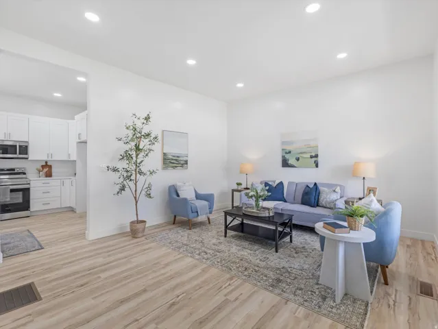 Open-concept living area featuring light wood-finish flooring, recessed lighting, and white wall finishes