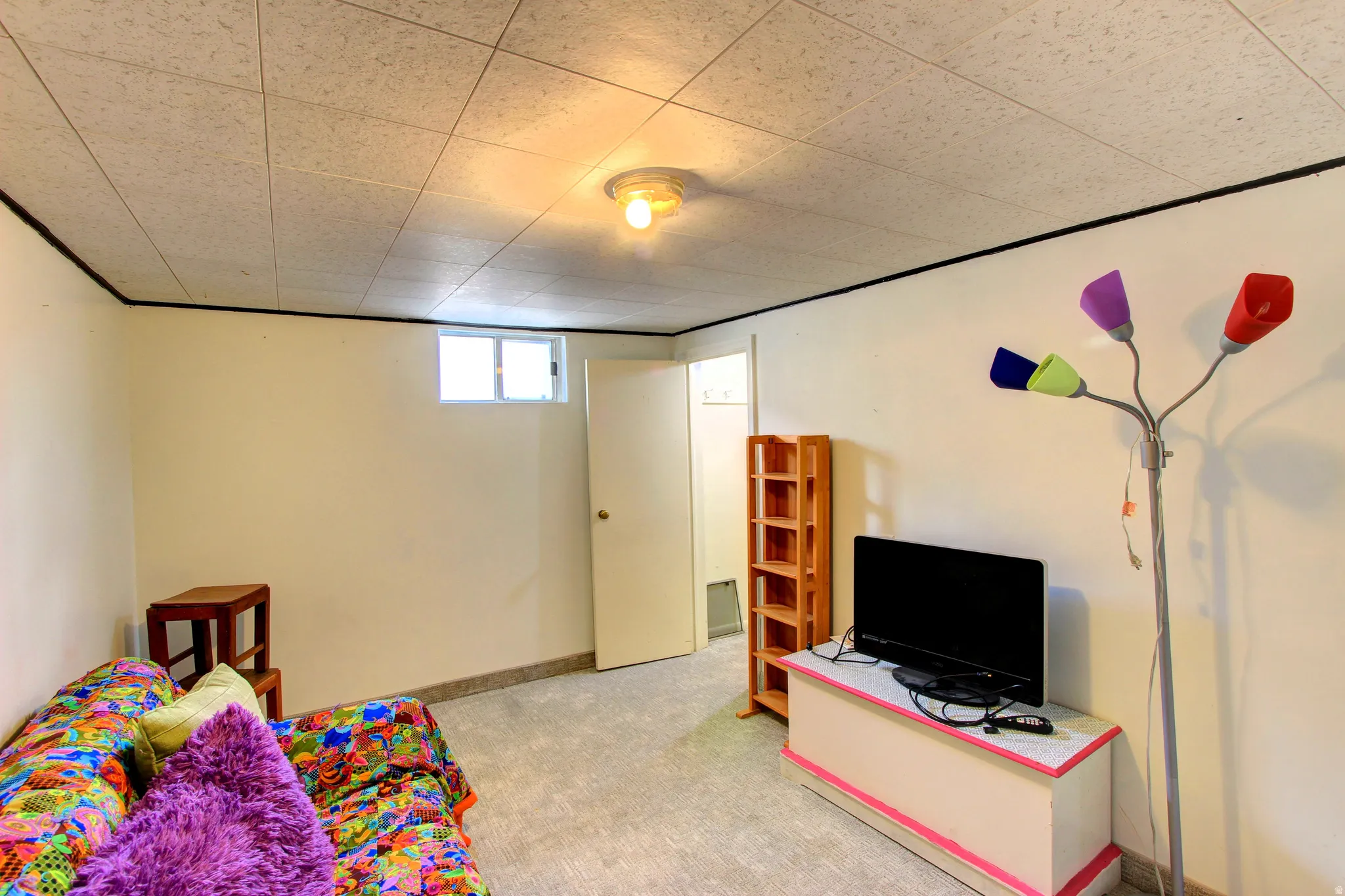 Finished room featuring a drop ceiling, light-colored walls, and a single window