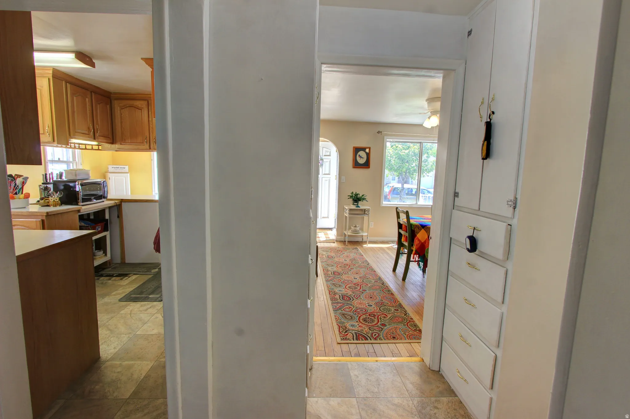 Hallway with built-in cabinetry, wood-finish flooring, and a kitchen featuring wood cabinetry and tile flooring