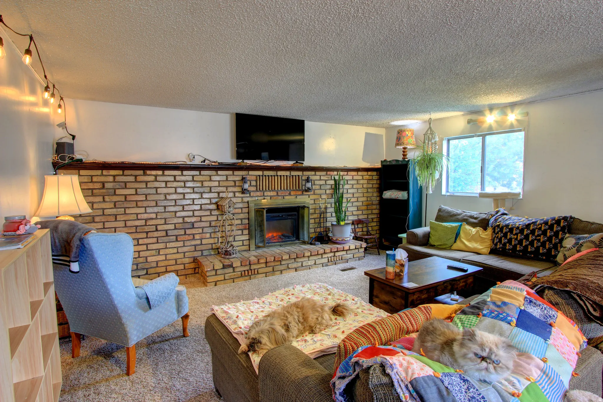 Brick-faced fireplace with an integrated electric insert and a substantial wood mantle